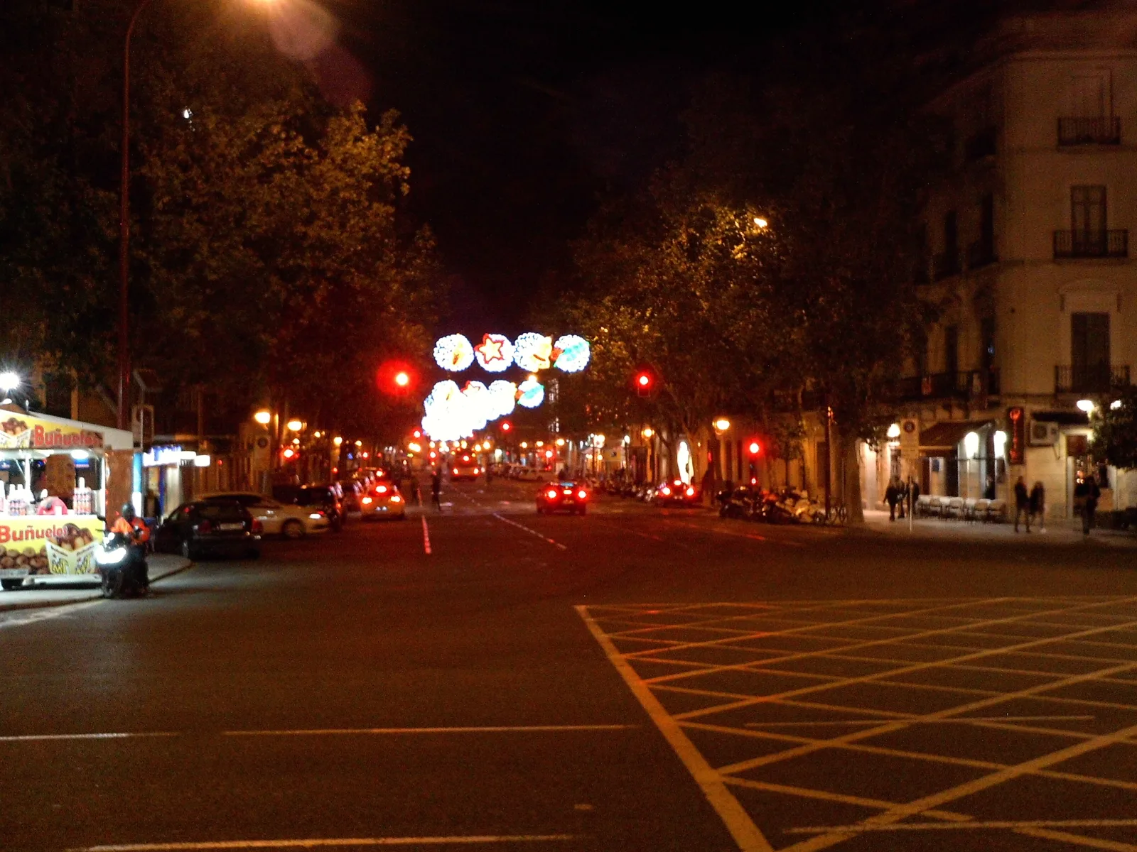A Seville street strung with warm Christmas lights after dark